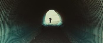 Movie still from “Run & Gun” (2022), directed by Christopher Borrelli – A man walking down a ramp in a tunnel; Extreme Wide shot, Low angle