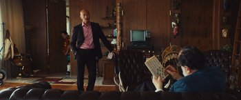 Movie still from “Run & Gun” (2022), directed by Christopher Borrelli – A man standing in front of two other people; Medium shot, Low angle