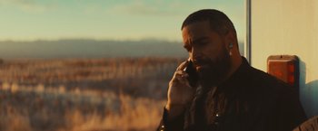 Movie still from “Run & Gun” (2022), directed by Christopher Borrelli – A bearded man talking on a cell phone outside; Close Up shot, Low angle
