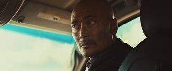 Movie still from “Run & Gun” (2022), directed by Christopher Borrelli – A man with a bald head sitting in a car; Close Up shot, Over the shoulder angle