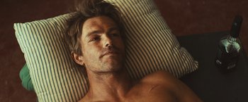 Movie still from “Run & Gun” (2022), directed by Christopher Borrelli – A man laying in bed with his head on a pillow; Close Up shot, Overhead angle