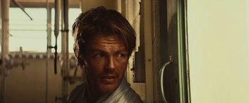 Movie still from “Run & Gun” (2022), directed by Christopher Borrelli – A person wearing a white shirt; Close Up shot, Low angle