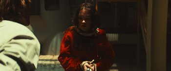 Movie still from “Run & Gun” (2022), directed by Christopher Borrelli – A young girl in a red jacket is holding a cigarette; Medium shot, High angle
