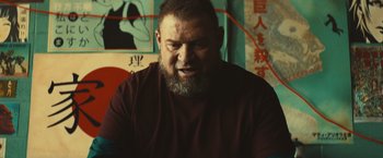 Movie still from “Run & Gun” (2022), directed by Christopher Borrelli – A man with a goatee and a beard; Close Up shot, Low angle