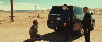 Movie still from “Run & Gun” (2022), directed by Christopher Borrelli – Two men are standing in front of a truck; Wide shot, Low angle