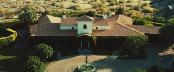 Movie still from “Run & Gun” (2022), directed by Christopher Borrelli – An aerial view of a large house with a fountain in the middle; Extreme Wide shot, High angle