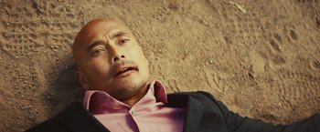 Movie still from “Run & Gun” (2022), directed by Christopher Borrelli – A man in a pink shirt and a black jacket; Close Up shot, Overhead angle