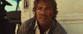 Movie still from “Run & Gun” (2022), directed by Christopher Borrelli – A person wearing a shirt and jacket; Close Up shot, Low angle