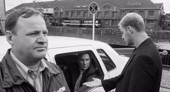 Movie still from “Run Lola Run” (1998), directed by Tom Tykwer – A man in a suit sitting in the back of a white car; Medium shot, Over the shoulder angle