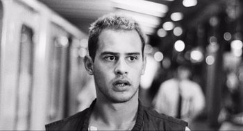 Movie still from “Run Lola Run” (1998), directed by Tom Tykwer – Black and white photograph of a young man in a crowd; Close Up shot, Low angle