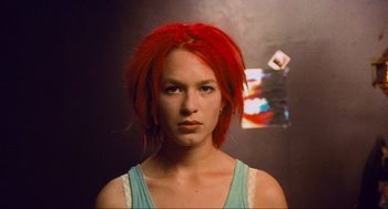 Movie still from “Run Lola Run” (1998), directed by Tom Tykwer – A woman with red hair is posing for a picture; Close Up shot, Low angle