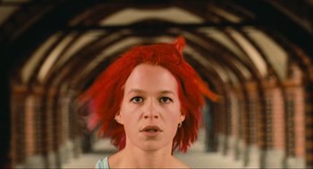 Movie still from “Run Lola Run” (1998), directed by Tom Tykwer – A woman with red hair is looking at the camera; Close Up shot, Low angle