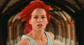 Movie still from “Run Lola Run” (1998), directed by Tom Tykwer – A woman with red hair is looking at the camera; Close Up shot, Low angle