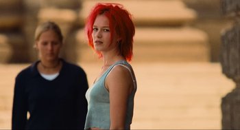 Movie still from “Run Lola Run” (1998), directed by Tom Tykwer – A woman with red hair standing next to a man; Medium shot, Low angle