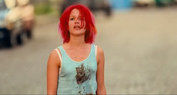 Movie still from “Run Lola Run” (1998), directed by Tom Tykwer – A woman with red hair is standing in the sand; Medium shot, Low angle