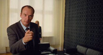 Movie still from “Run Lola Run” (1998), directed by Tom Tykwer – A man wearing a suit and tie sitting at a table; Medium shot, Low angle