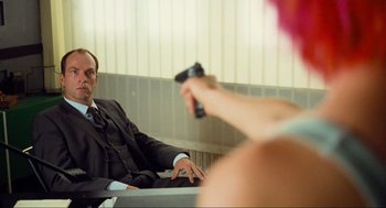 Movie still from “Run Lola Run” (1998), directed by Tom Tykwer – A man and a woman sitting in front of each other holding remotes; Medium shot, Over the shoulder angle