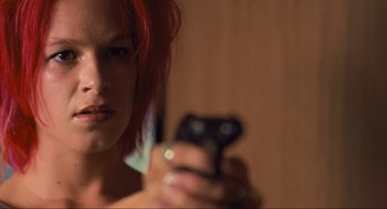 Movie still from “Run Lola Run” (1998), directed by Tom Tykwer – A woman holding a cell phone in front of a mirror; Close Up shot, Low angle