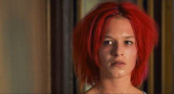Movie still from “Run Lola Run” (1998), directed by Tom Tykwer – A woman with bright red hair stares into the camera; Close Up shot, Low angle