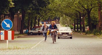 Movie still from “Run Lola Run” (1998), directed by Tom Tykwer – A man and a woman riding a bike down a street; Wide shot, High angle