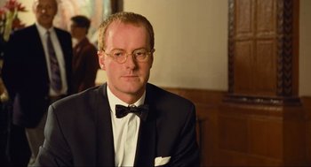 Movie still from “Run Lola Run” (1998), directed by Tom Tykwer – A man in a suit and bow tie; Close Up shot, Over the shoulder angle