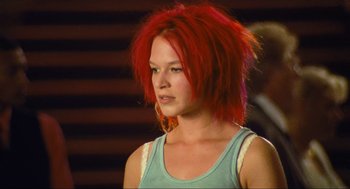 Movie still from “Run Lola Run” (1998), directed by Tom Tykwer – A woman with red hair is standing in front of a wall; Close Up shot, Low angle