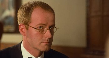 Movie still from “Run Lola Run” (1998), directed by Tom Tykwer – A person wearing a suit and glasses; Close Up shot, Low angle