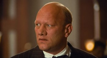 Movie still from “Run Lola Run” (1998), directed by Tom Tykwer – A bald man in a suit and tie looking to his left; Close Up shot, High angle