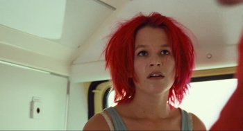 Movie still from “Run Lola Run” (1998), directed by Tom Tykwer – A woman with red hair is standing in front of a window; Close Up shot, Low angle