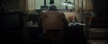 Movie still from “Samaritan” (2022), directed by Julius Avery – An old man sitting at a desk in front of a computer; Medium shot, Low angle
