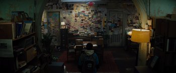 Movie still from “Samaritan” (2022), directed by Julius Avery – A person sitting in front of a wall covered with papers; Extreme Wide shot, High angle