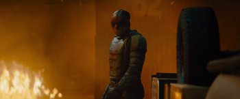 Movie still from “Samaritan” (2022), directed by Julius Avery – A man with a helmet on standing next to a wall; Medium shot, Low angle