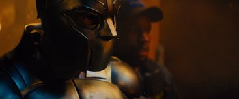 Movie still from “Samaritan” (2022), directed by Julius Avery – A person wearing a metal helmet; Close Up shot, Over the shoulder angle