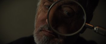 Movie still from “Samaritan” (2022), directed by Julius Avery – An older man looking through a magnifying glass; Extreme Close Up shot, Low angle