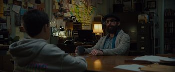 Movie still from “Samaritan” (2022), directed by Julius Avery – A man sitting at a wooden table with a cup of coffee; Medium shot, Over the shoulder angle