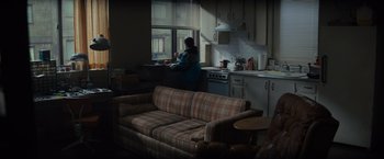 Movie still from “Samaritan” (2022), directed by Julius Avery – A woman in a plaid jacket in a kitchen; Wide shot, High angle
