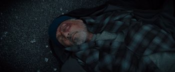 Movie still from “Samaritan” (2022), directed by Julius Avery – An older man laying on the ground with his eyes closed; Close Up shot, Overhead angle