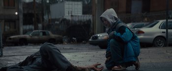 Movie still from “Samaritan” (2022), directed by Julius Avery – A young boy sitting on the ground next to a man; Medium shot, Low angle