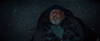 Movie still from “Samaritan” (2022), directed by Julius Avery – An old man laying on the ground with a blanket over him; Close Up shot, Overhead angle