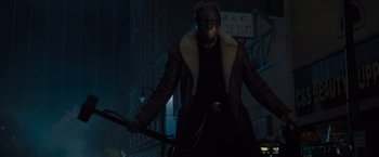Movie still from “Samaritan” (2022), directed by Julius Avery – A man in a leather jacket holding a metal pole; Medium shot, Low angle