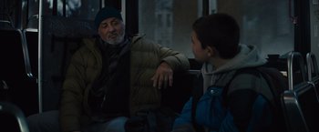 Movie still from “Samaritan” (2022), directed by Julius Avery – An older man and a young boy sitting on a bus; Medium shot, Over the shoulder angle
