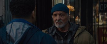 Movie still from “Samaritan” (2022), directed by Julius Avery – An older man wearing a blue hat talking to a younger man; Close Up shot, Over the shoulder angle