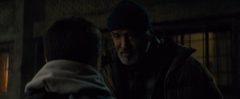 Movie still from “Samaritan” (2022), directed by Julius Avery – An older man wearing a blue hat talking to a younger man; Close Up shot, Over the shoulder angle