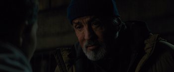 Movie still from “Samaritan” (2022), directed by Julius Avery – An old man with a beard wearing a blue hat; Close Up shot, Over the shoulder angle