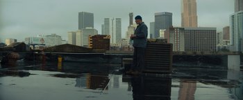 Movie still from “Samaritan” (2022), directed by Julius Avery – A man standing on top of a building in the rain; Wide shot, Low angle