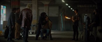 Movie still from “Samaritan” (2022), directed by Julius Avery – A man sitting on a chair with a woman sitting next to him; Wide shot, Low angle