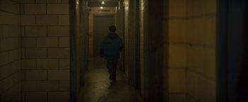 Movie still from “Samaritan” (2022), directed by Julius Avery – A man walking down a hallway in a building; Wide shot, High angle