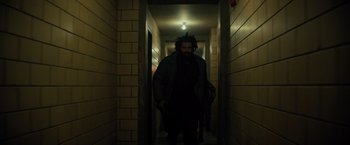 Movie still from “Samaritan” (2022), directed by Julius Avery – A man walking down a hallway in a building; Medium shot, Low angle