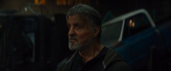 Movie still from “Samaritan” (2022), directed by Julius Avery – An older man with a gray beard looking to his left; Close Up shot, Low angle