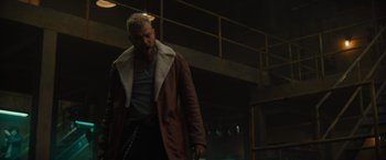 Movie still from “Samaritan” (2022), directed by Julius Avery – A man in a brown jacket is standing in a dark room; Medium shot, Low angle